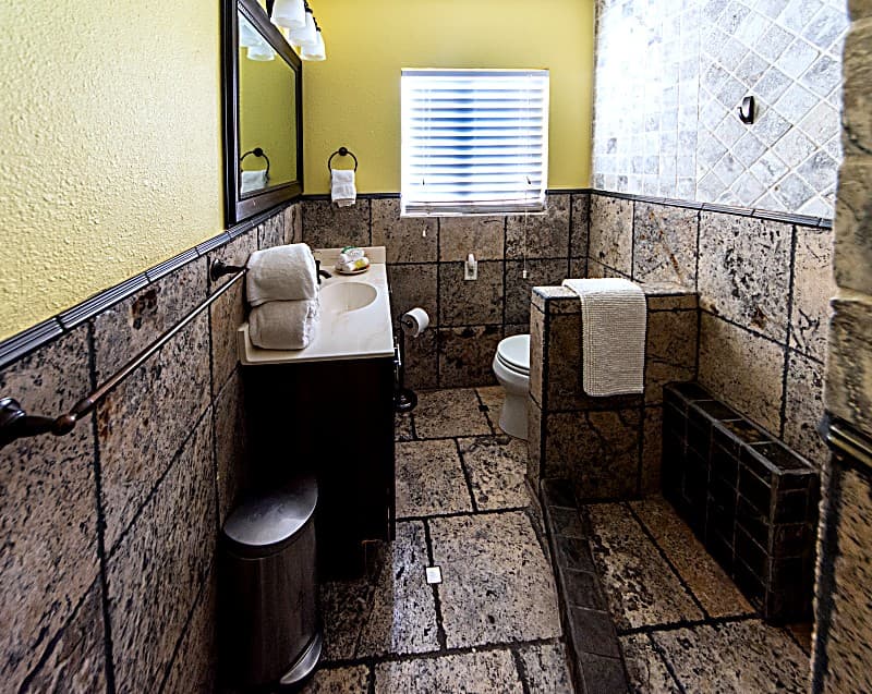 Stone-tiled bathroom with vanity, walk-in shower, and fresh towels