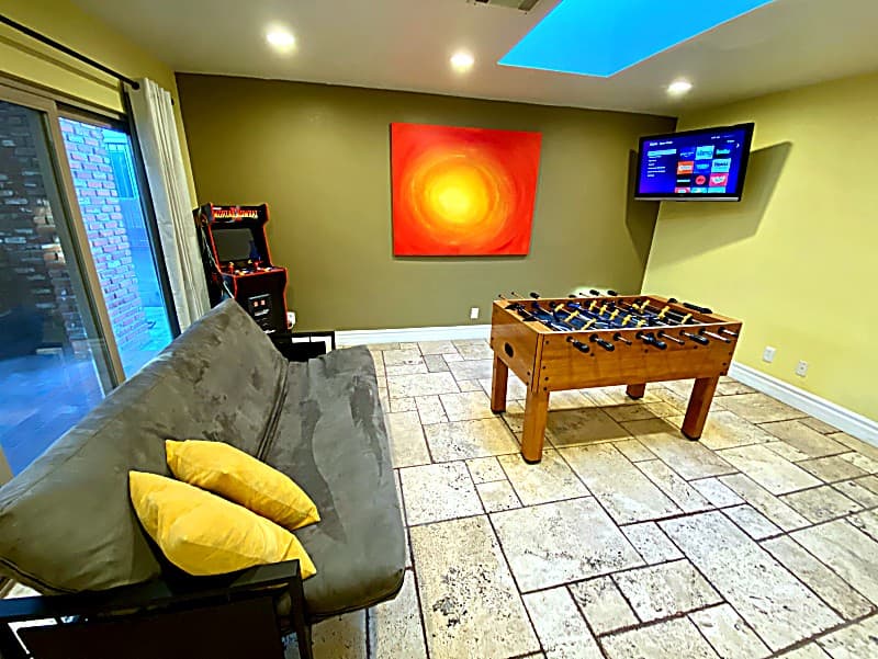 Game room with foosball table, arcade cabinet, futon, and wall-mounted TV