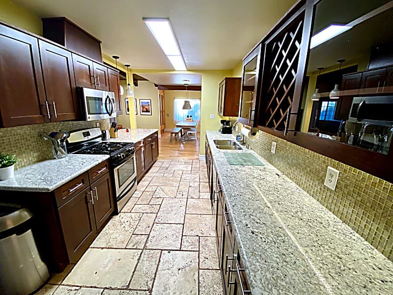 Remodeled galley kitchen with granite counters, gas range, and stainless appliances