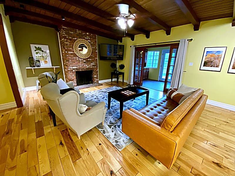 Living room with leather sofa, brick fireplace, and wood-beamed ceiling
